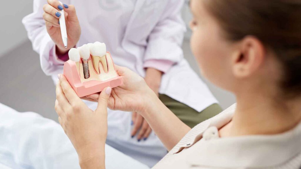 A patient holding a dental model while a dentist points to it with a pen