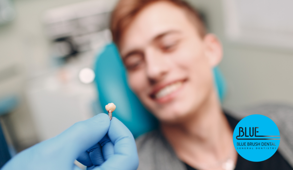 A dentist's gloved hand holding a dental implant with a smiling patient in the background